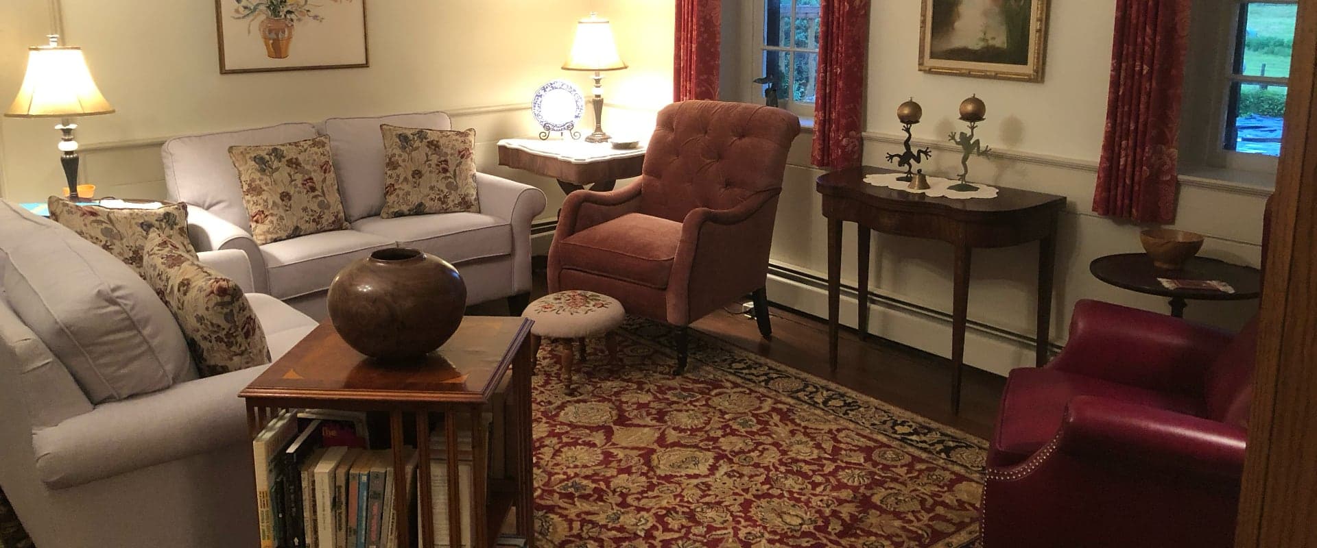 Cozy living room with a pale sofa, a pink chair, a wooden table, and decorative lamps.