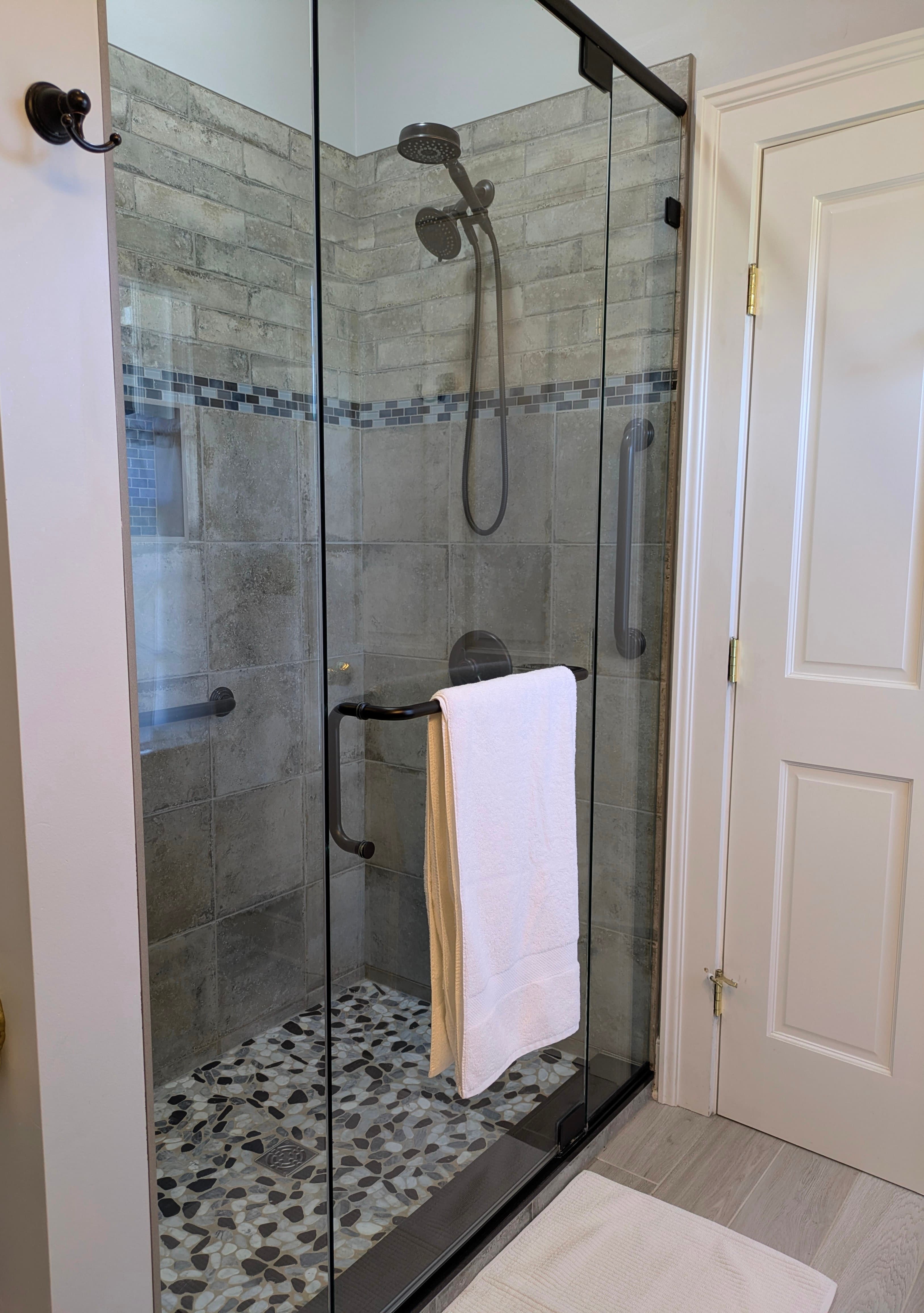 Shower with glass doors, grab bars, pebble floor, fixed and hand-held shower heads