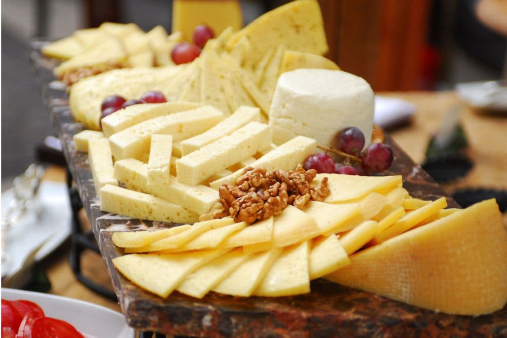 A platter of various cheeses, garnished with grapes and nuts.