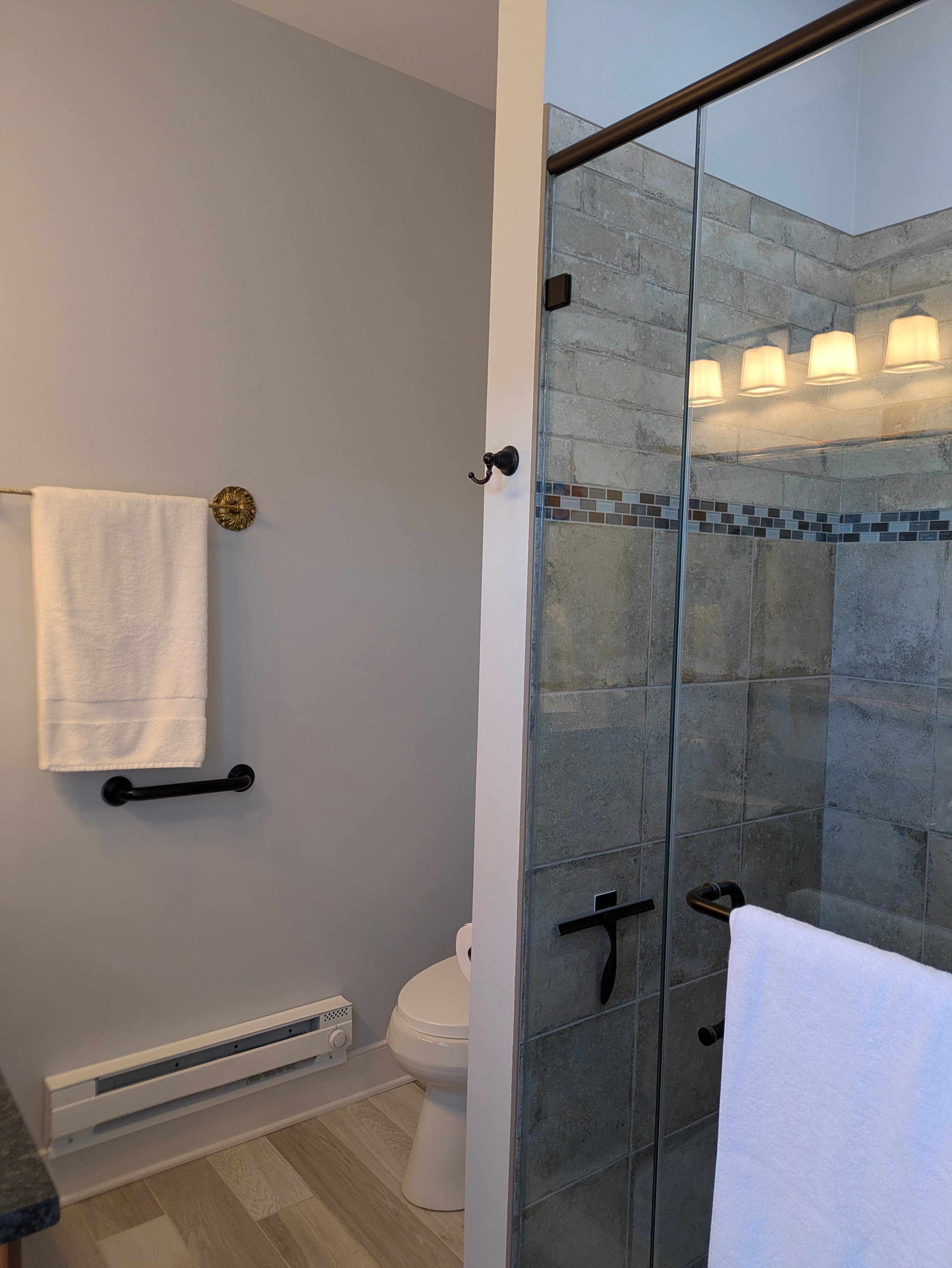 New bathroom with space heater, vintage towel bars, space heater, glass doors to shower