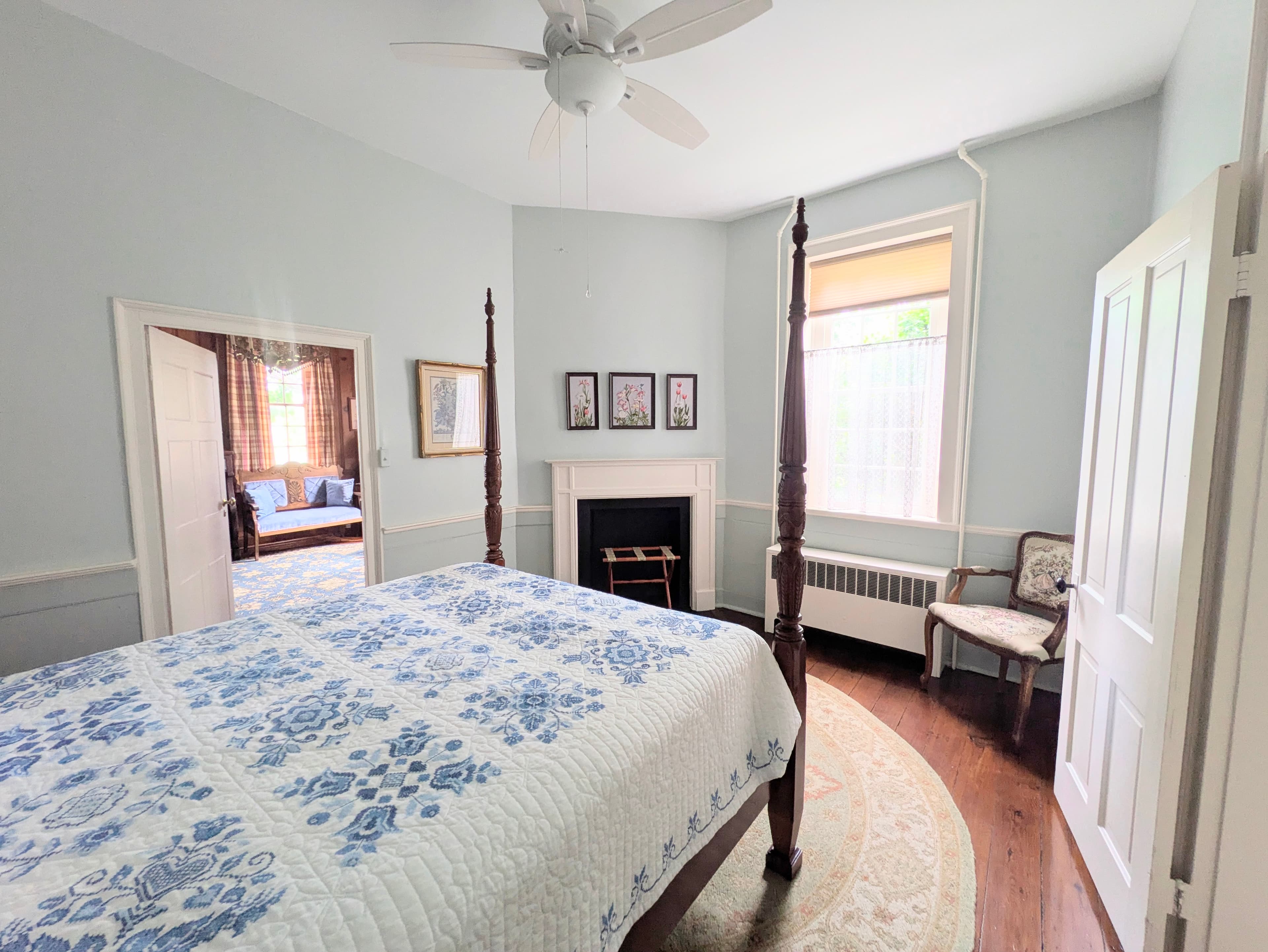 Looking back toward the door across the bed shows the fireplace, window, and bedroom chair