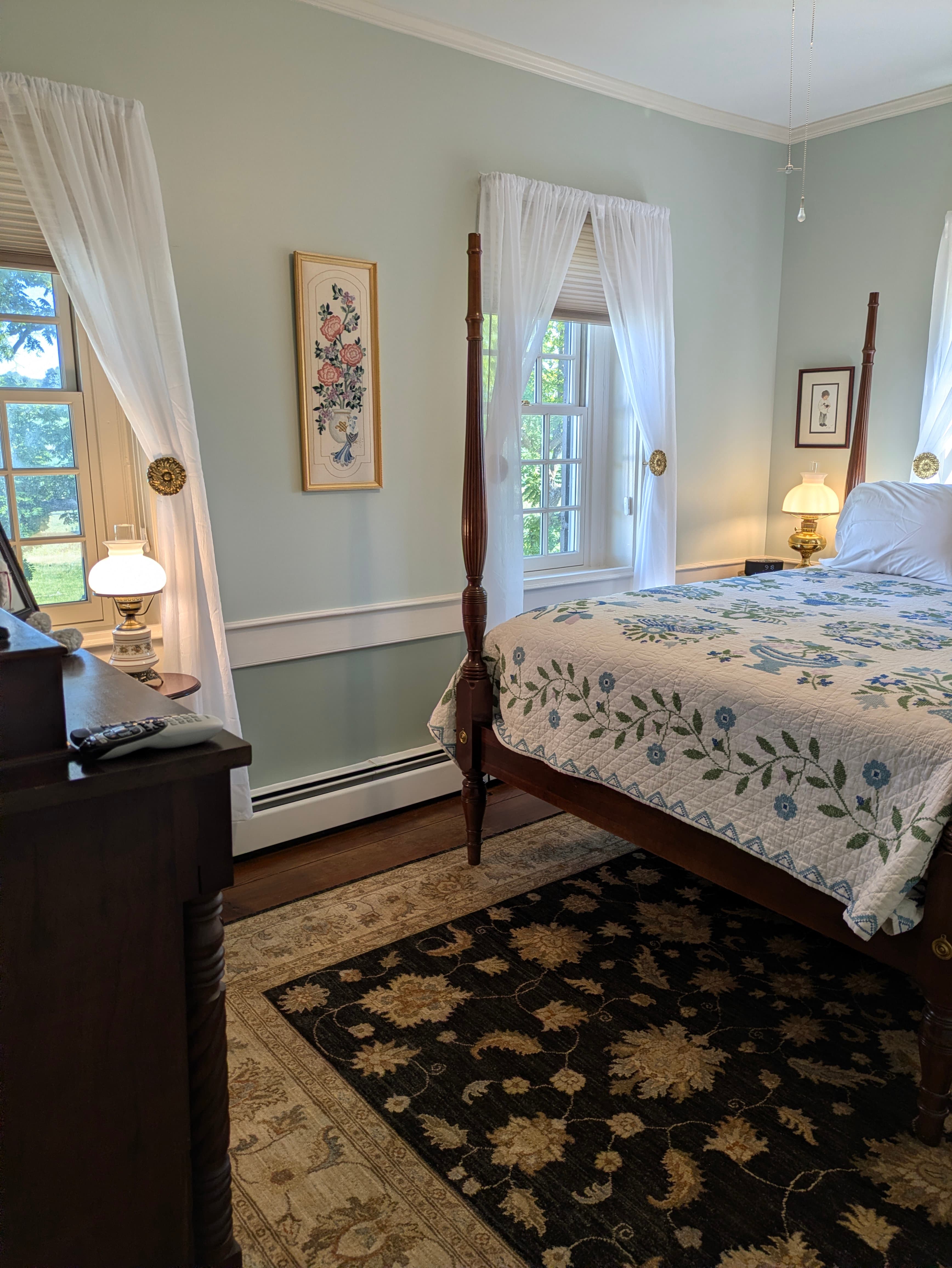 Bedroom with dresser to left, and two windows looking out over the front lawn