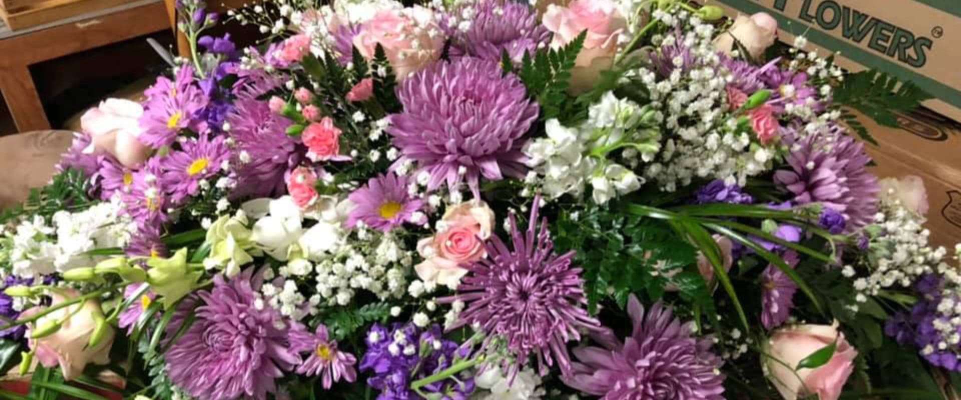 A vibrant bouquet featuring purple asters, pink roses, and assorted greenery.