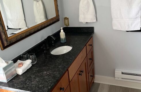 Bathroom with soapstone countertop, white towels, mirror, clock