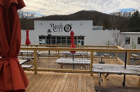 Outdoor patio of a brewery with several patio tables with closed red umbrellas