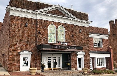 Tall brown brick performing arts center with white doors and trim and tall arched windows