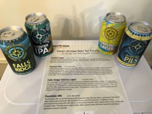 Four cans of beer from Seven Arrows Brewing Company around a list of beers with descriptions of each.