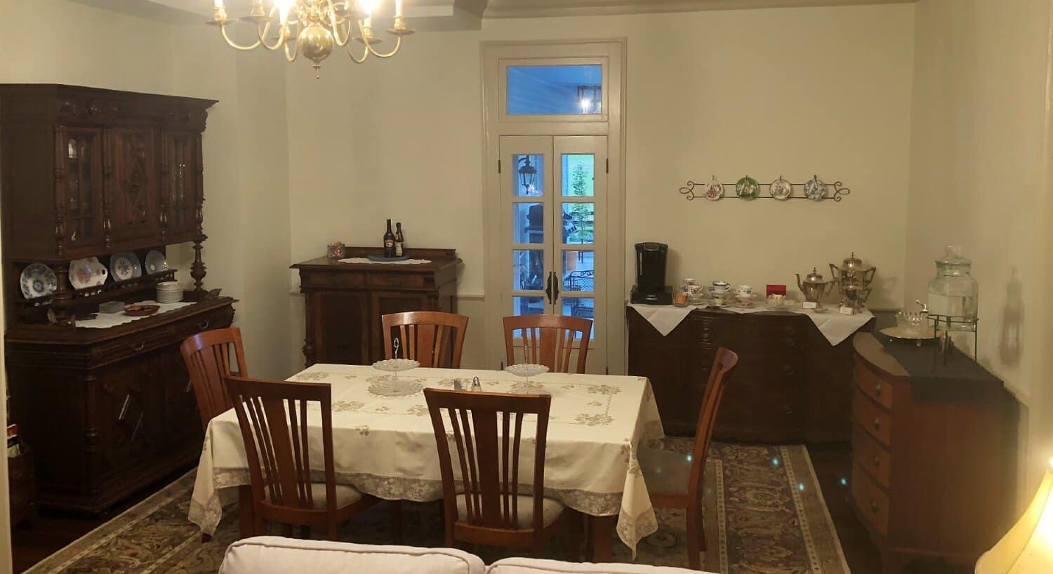 Dining area with white walls and dark wood table set for six, hutch and three buffet tables