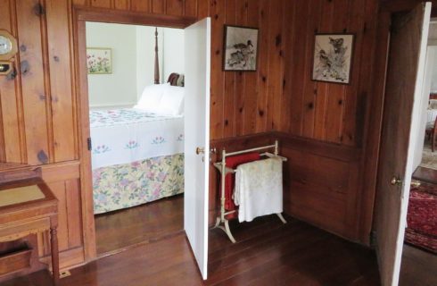 Room with hardwood floors showing open doorways into a bedroom and a dining room