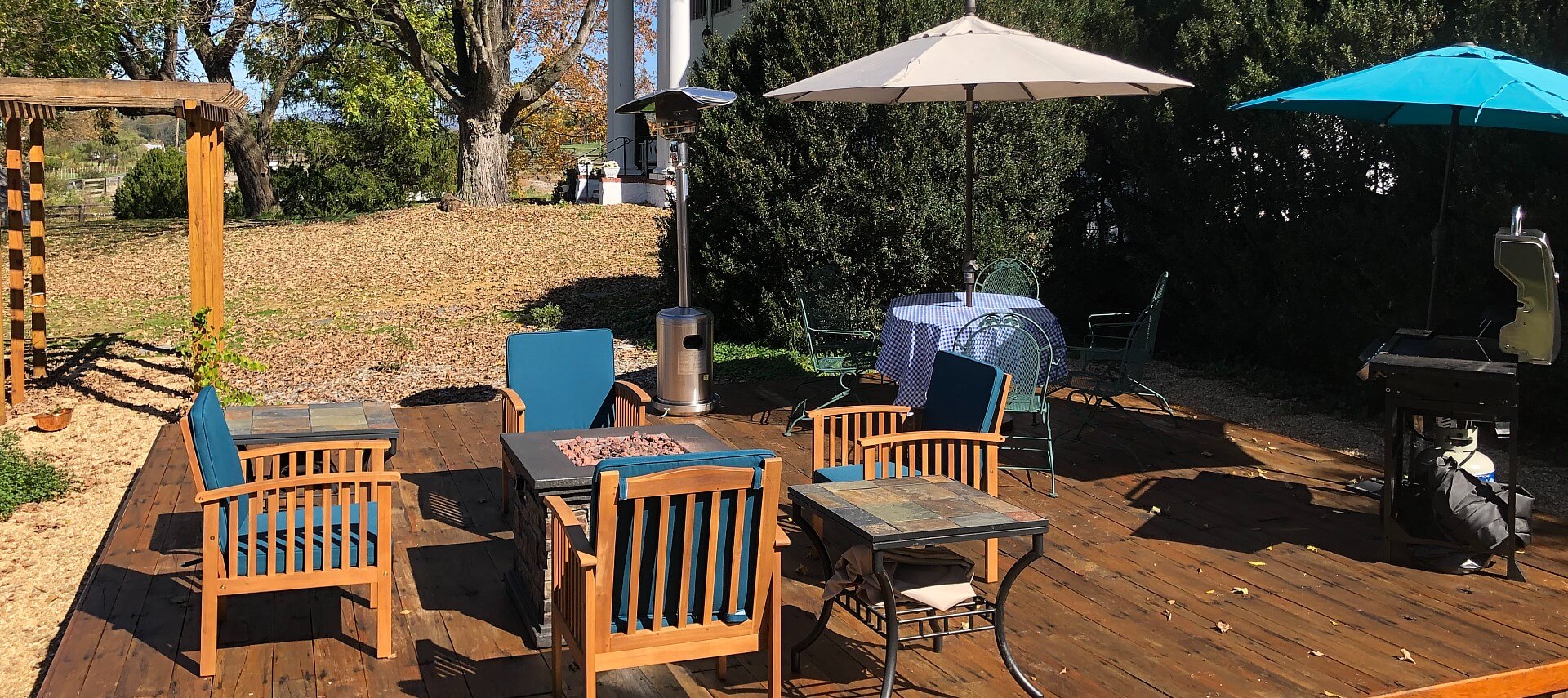 Outdoor deck with fireplace table and four chairs, patio table with umbrella, and BBQ grill