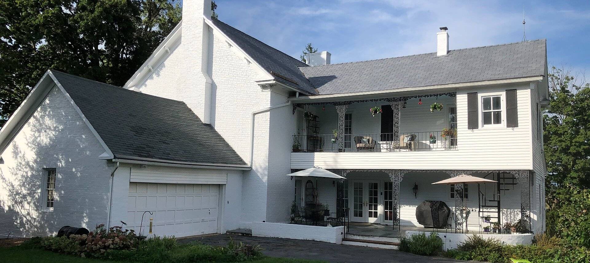 Large white brick home with grey roof and upper and lower outdoor porches